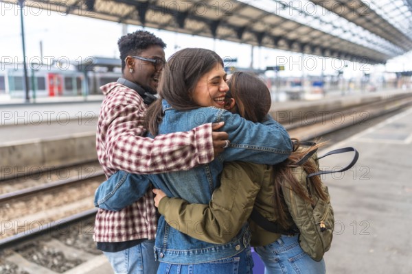 Three happy students hugging each other at the train station, excited for their journey or happy to meet again