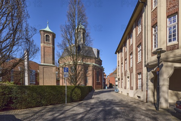 Meeting place at the Clemenskirche for people in social need, Clemenskirche, church, Baroque architectural style, architect Johann Conrad Schlaun, brick building, bare winter trees, hedge, blue cloudless sky, An der Clemenskirche, Münster, Münsterland, independent city, North Rhine-Westphalia, Germany, Europe