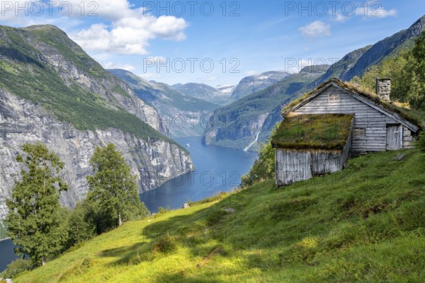 Blomberg Gård, historic mountain farm with grass roof on a steep mountainside above the Geirangerfjord, view of idyllic fjord landscape, near Geiranger, Møre og Romsdal, Norway, Europe