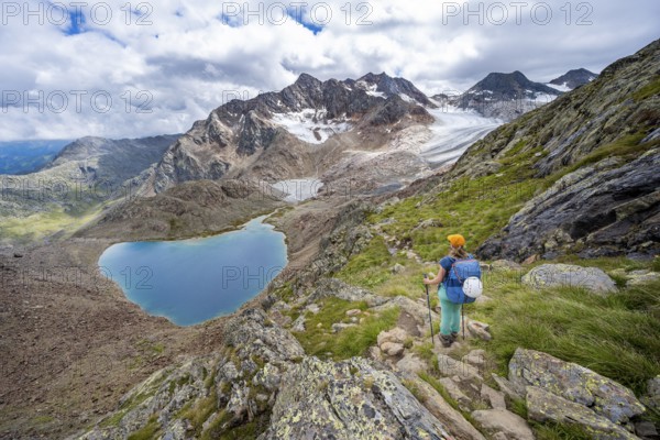 Mountaineer on hiking trail in dramatic high mountain landscape, view of mountains with mountain lake Vogelhüttensee and glacier Übeltalferner, Stubai Alps, South Tyrol, Italy, Europe
