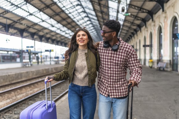 Young multi ethnic couple walking together with luggage at a train station platform, enjoying their vacation
