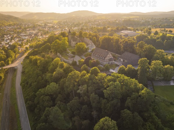 A village view from above with church and half-timbered houses on a tree-covered hill, event and wedding location Lorch Monastery, Lorch, Germany, Europe