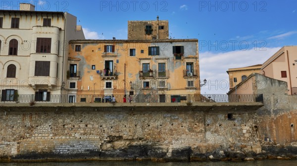 Houses with colourful facades and balconies along a stone seawall, boat trip around the island of Ortigia, Isola di Ortigia, Syracuse, Sicily, Italy, Europe