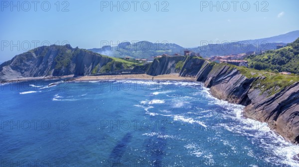 Breathtaking aerial view of zumaia's unique flysch coastline, showcasing its dramatic cliffs and inviting blue waters under a vibrant summer sky, Spain.