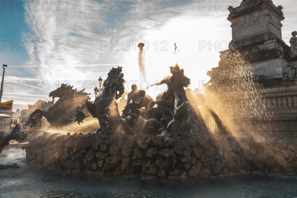 The majestic monument aux girondins fountain, located in place des quinconces, bordeaux, is illuminated by the golden rays of the setting sun