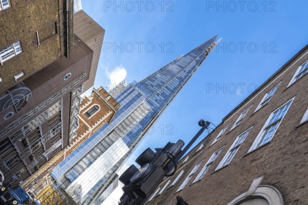 Low angle view of the shard skyscraper dominating the skyline above traditional brick buildings in london, uk, highlighting the contrast between old and new