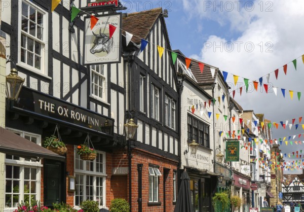 Bunting flags decorating buildings in historic street, The Ox Row Inn and shops, Butcher Row, Salisbury, Wiltshire, England, UK
