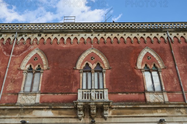 Red façade of a building with Gothic windows and decorative details, Ortigia Island, Isola di Ortigia, Historic Centre, Syracuse, Sicily, Italy, Europe