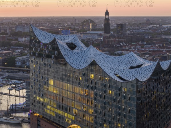 Aerial view of the Elbphilharmonie at sunset with illuminated windows and view over Hamburg and the main church St Michaelis (Michel), Hamburg, Germany, Europe