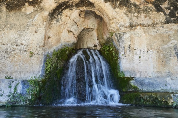 Nymph grotto, Small waterfall flowing from a rocky cave with moss growth, Neapolis Archaeological Park, Syracuse, Sicily, Italy, Europe