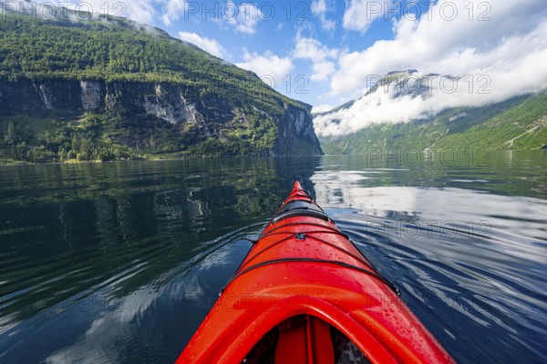 Kayak trip on the Geirangerfjord, tip of a red kayak in the fjord with reflection, atmospheric fjord landscape, first person view at Geiranger, Møre og Romsdal, Norway, Europe