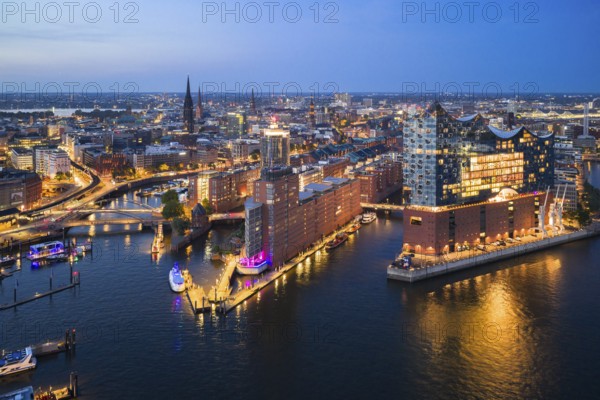 Aerial view of the Elbphilharmonie at blue hour with illuminated windows and view over the Speicherstadt and Hafencity, Hamburg, Germany, Europe
