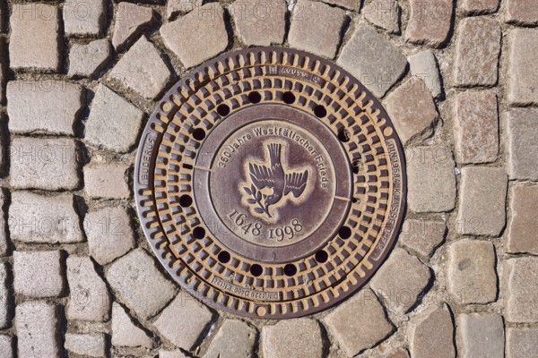 Manhole cover, dove of peace, 350 years of the Peace of Westphalia, 1648 to 1998, biblical symbol, cobblestones, Münster, Münsterland, independent city, North Rhine-Westphalia, Germany, Europe