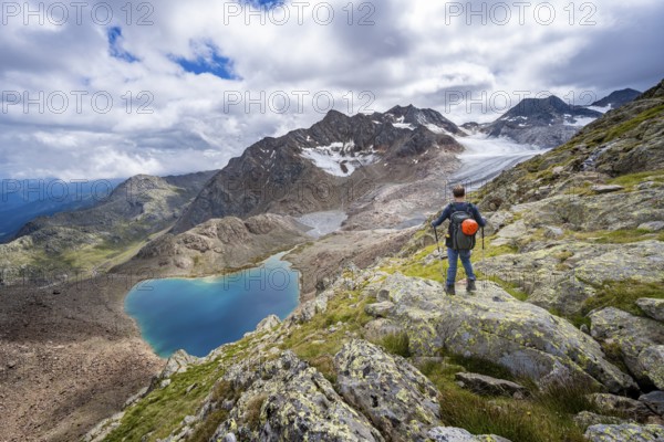 Mountaineer in front of dramatic high mountain landscape, view of mountain lake Vogelhüttensee and glacier Übeltalferner, Stubai Alps, South Tyrol, Italy, Europe