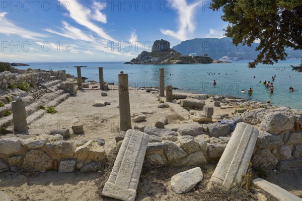 Ancient ruins in front of a rocky coast with a view of the clear sea and a small, mountainous island, Agios Stefanos Beach, Agios Stefanos Basilica, Agios Nikolaos Chapel, Kastri Island, Kos, Dodecanese, Greek Islands, Greece, Europe