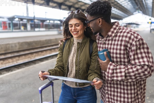 Happy tourists consulting map at train station while waiting for train, planning their next destination