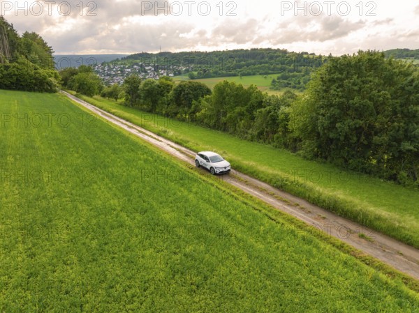 Car drives through a wide, green landscape with hills and villages on the horizon, Deer E- CarSharing, Renault Megane electric car, Calw, Black Forest, Germany, Europe