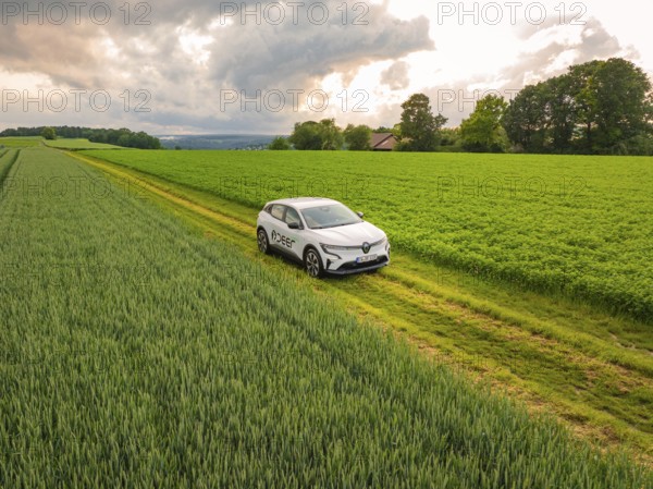 A car on a path between fields under dark rain clouds in a rural area, Deer E- CarSharing, Renault Megane electric car, Calw, Black Forest, Germany, Europe