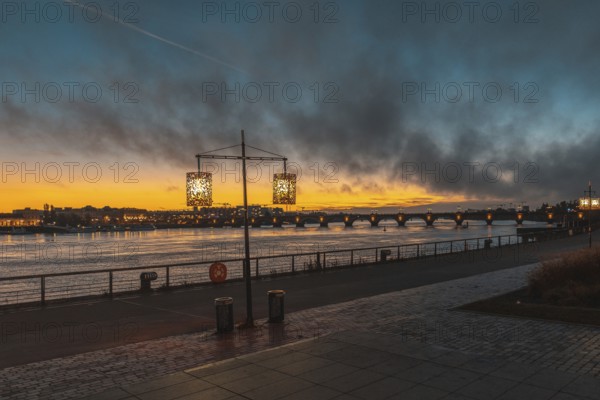 Scenic view of bordeaux cityscape illuminating at sunset over garonne river with pont de pierre bridge in the background