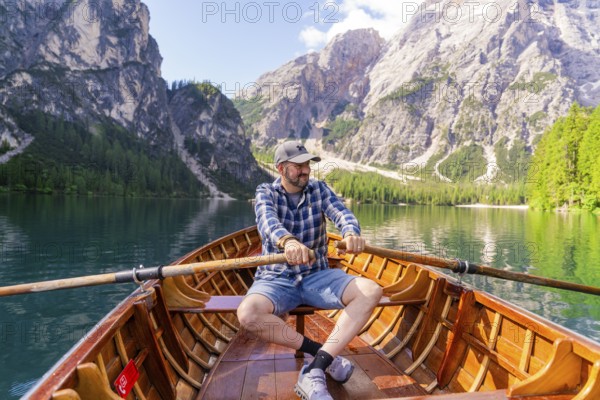 Man rowing on a mountain lake, surrounded by pine trees and steep mountain slopes, Lake Braies, South Tyrol, Dolomites, Italy, Europe