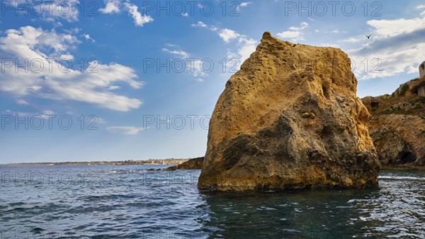 A large rock in the sea under a blue sky with white clouds, boat trip around the island of Ortigia, Isola di Ortigia, Syracuse, Sicily, Italy, Europe