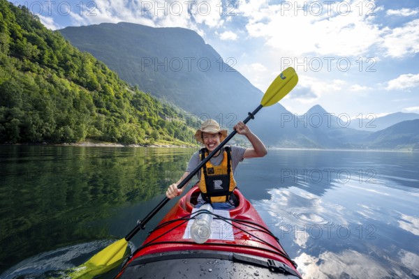 Kayak trip on the Geirangerfjord, Young man paddling in a kayak, atmospheric fjord landscape, Møre og Romsdal, Norway, Europe