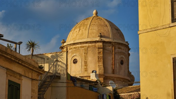 Historic dome in an old town setting with yellow buildings and palm trees, blue sky, Ortigia Island, Isola di Ortigia, Historic old town, Syracuse, Sicily, Italy, Europe