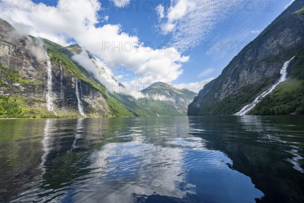 Atmospheric fjord landscape with waterfall The Seven Sisters and Freier Waterfall, Geirangerfjord with reflection, Møre og Romsdal, Norway, Europe