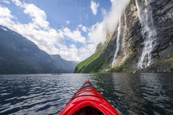 Kayak trip on the Geirangerfjord at the waterfall The Seven Sisters, tip of a red kayak in the fjord, atmospheric fjord landscape, first person view, near Geiranger, Møre og Romsdal, Norway, Europe