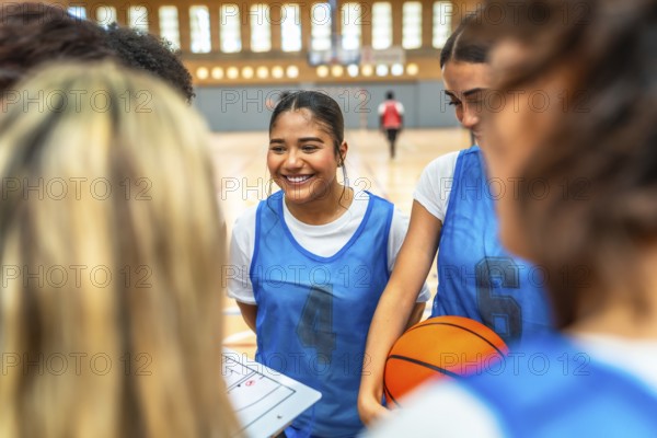 Happy basketball players gathering in a gym, discussing game strategies and fostering teamwork during an energetic training session