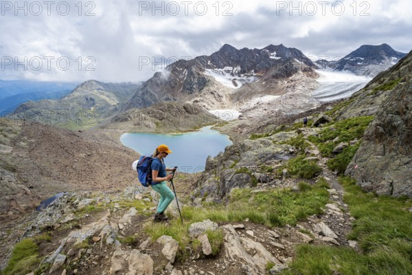 Mountaineer on hiking trail in dramatic high mountain landscape, view of mountains with mountain lake Vogelhüttensee and glacier Übeltalferner, Stubai Alps, South Tyrol, Italy, Europe
