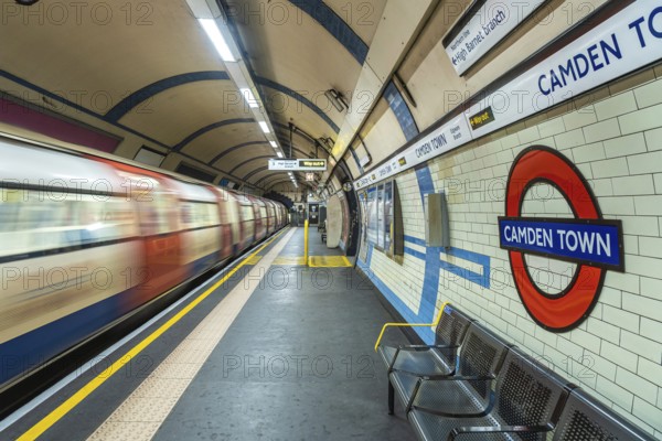 Motion blur of a london underground train arriving at camden town station with its distinctive tiled walls and roundel