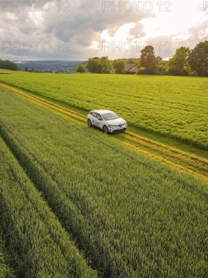 Car on a country lane, surrounded by fields and a row of trees under a cloudy sky, Deer E- CarSharing, Renault Megane electric car, Calw, Black Forest, Germany, Europe