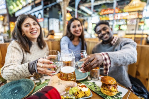 Happy friends enjoying a meal together, raising their glasses in a cheerful toast at a vibrant restaurant