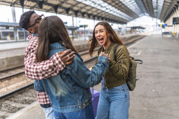 Three cheerful multi ethnic friends greeting each other on a train station platform, excited for their journey