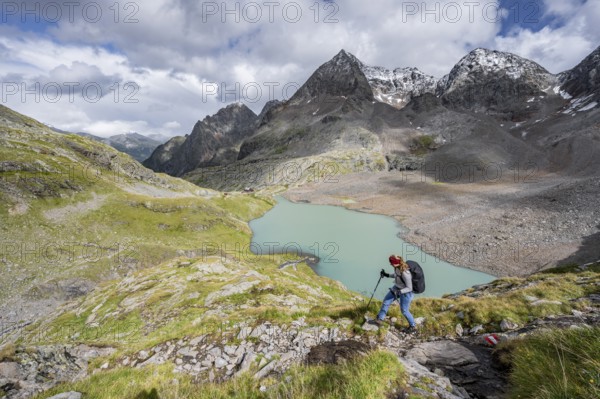 Mountaineer on hiking trail in mountain landscape, view of turquoise-blue mountain lake Großer Gradensee, behind summit of Petzeck and Kruckelkopf, Schober group, Hohe Tauern National Park, Carinthia, Austria, Europe