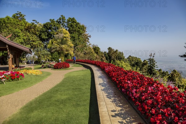 Colorful lush flower gardens line the perimeter of the mountain top Doi Tung Royal Villa lawn with a panoramic view of the surrounding land at the Doi Tung tourist attraction in Chiang Rai, Thailand, Asia
