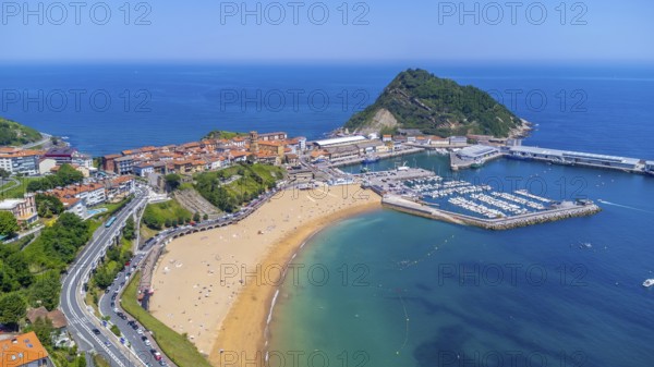 Aerial view of getaria, a charming coastal town in the basque country, spain, showcasing its picturesque harbor, sandy beach, and the iconic mount san anton on a sunny summer day