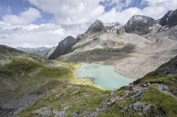 Mountaineer on hiking trail, view of turquoise-blue mountain lake Großer Gradensee, behind summit of Petzeck and Kruckelkopf, Schober group, Hohe Tauern National Park, Carinthia, Austria, Europe