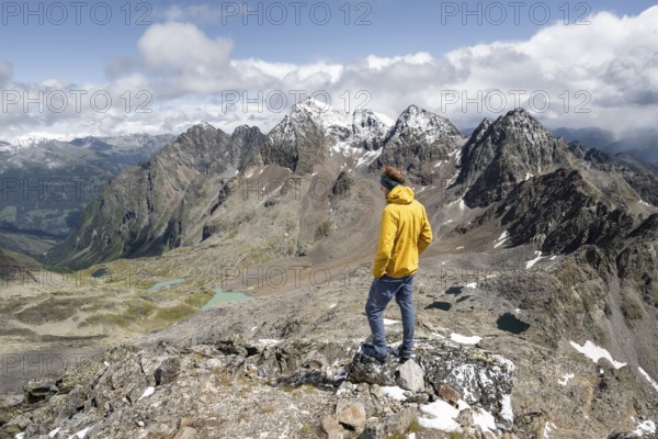 Mountaineer in rocky mountain landscape, at the summit of Keeskopf, behind summit of Petzeck, Hoher Perschitzkopf and Kruckelkopf, Schober group, Hohe Tauern National Park, Carinthia, Austria, Europe