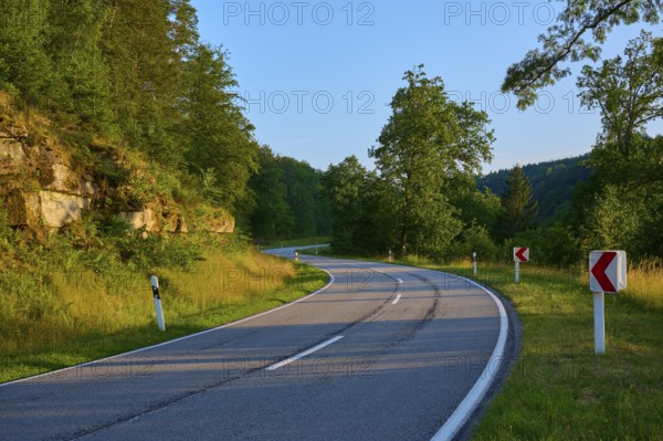 Rural road winds through wooded area in the evening sun, summer, Ernsttal, Mudau, Odenwald, Baden-Württemberg, Germany, Europe