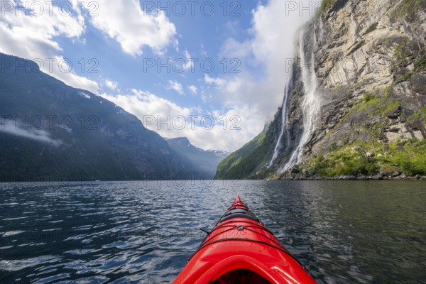 Kayak trip on the Geirangerfjord at the waterfall The Seven Sisters, tip of a red kayak in the fjord, atmospheric fjord landscape, first person view, near Geiranger, Møre og Romsdal, Norway, Europe