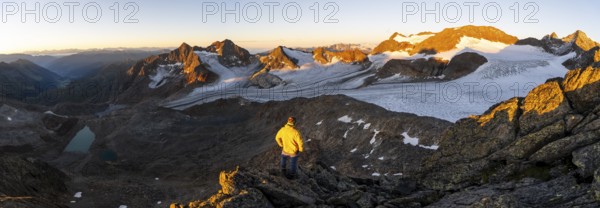 Mountaineers in front of a picturesque high mountain landscape at sunrise with alpenglow, blue glacial lakes, glaciers and rocky mountain peaks in the morning light, view at the Becher on mountain peaks Königshofspitz and Sonklarspitze and Schwarzwandspitz with glacier Übeltalferner, Stubai Alps, South Tyrol, Italy, Europe