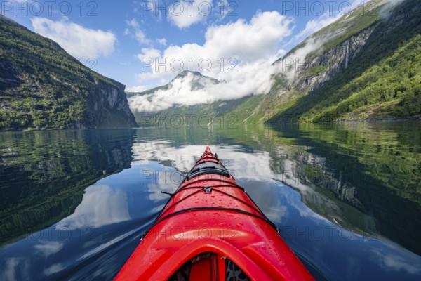 Kayak trip on the Geirangerfjord, tip of a red kayak in the fjord with reflection, atmospheric fjord landscape, first person view at Geiranger, Møre og Romsdal, Norway, Europe