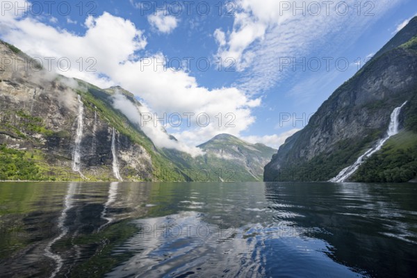 Atmospheric fjord landscape with waterfall The Seven Sisters and Freier Waterfall, Geirangerfjord with reflection, Møre og Romsdal, Norway, Europe