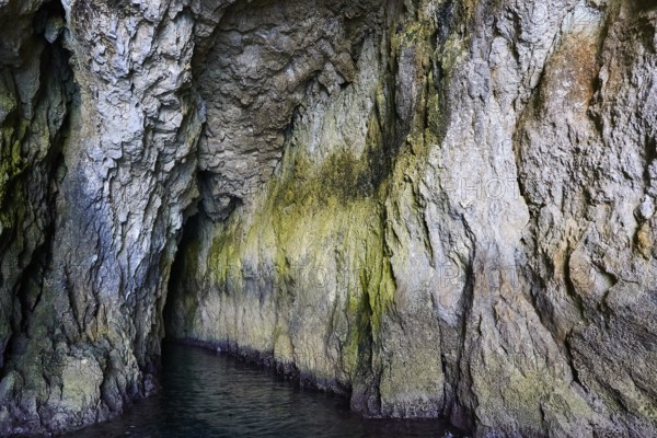 Entrance to a dark cave with irregular rock structures, boat trip around the island of Ortigia, Isola di Ortigia, Syracuse, Sicily, Italy, Europe