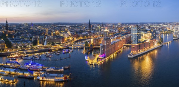 Panorama aerial view of the Elbphilharmonie at blue hour with illuminated windows and view over Landungsbrücken, Speicherstadt and Hafencity, Hamburg, Germany, Europe