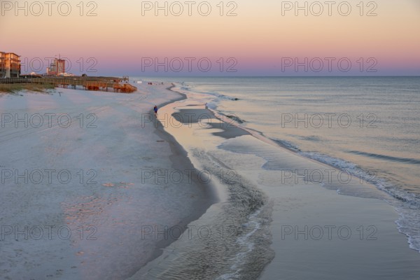Woman and child walking along the Gulf of Mexico beach as the sun rises over the Gulf of Mexico at Gulf Shores, Alabama