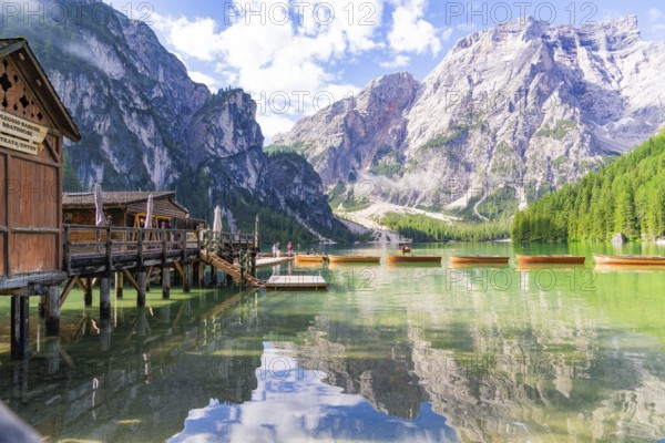 Wooden huts on the lakeshore against a majestic mountain backdrop and calm waters, Lake Braies, South Tyrol, Dolomites, Italy, Europe