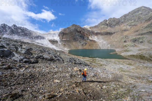 Mountaineer on a hiking trail, mountain landscape with limestone rocks between granite mountains, mountain lake Hinterer Senner Egetsee and mountain peak of the Moarer Weißen, Seven Lakes Hike, Stubai Alps, near Ridnaun, South Tyrol, Italy, Europe